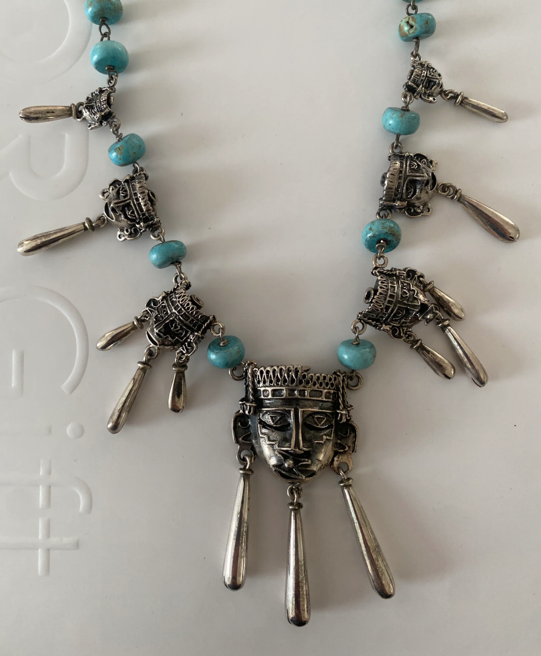 Indómita – Collar de Xipe Tótec con máscaras escalonadas y cuentas de pasta de turquesa - Joyería Mixteca